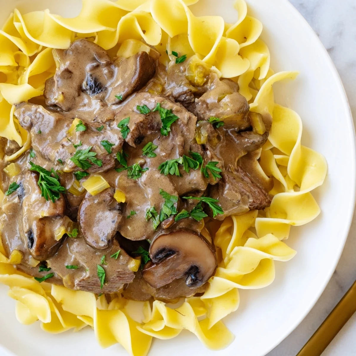 A close-up of savory beef stroganoff, the rich gravy glistening with creamy accents.