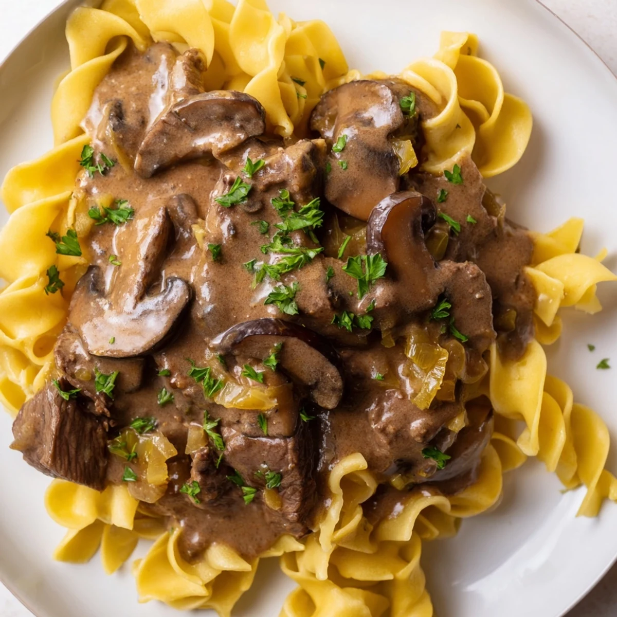 Warm egg noodles topped with a generous portion of creamy beef stroganoff, perfect for dinner.