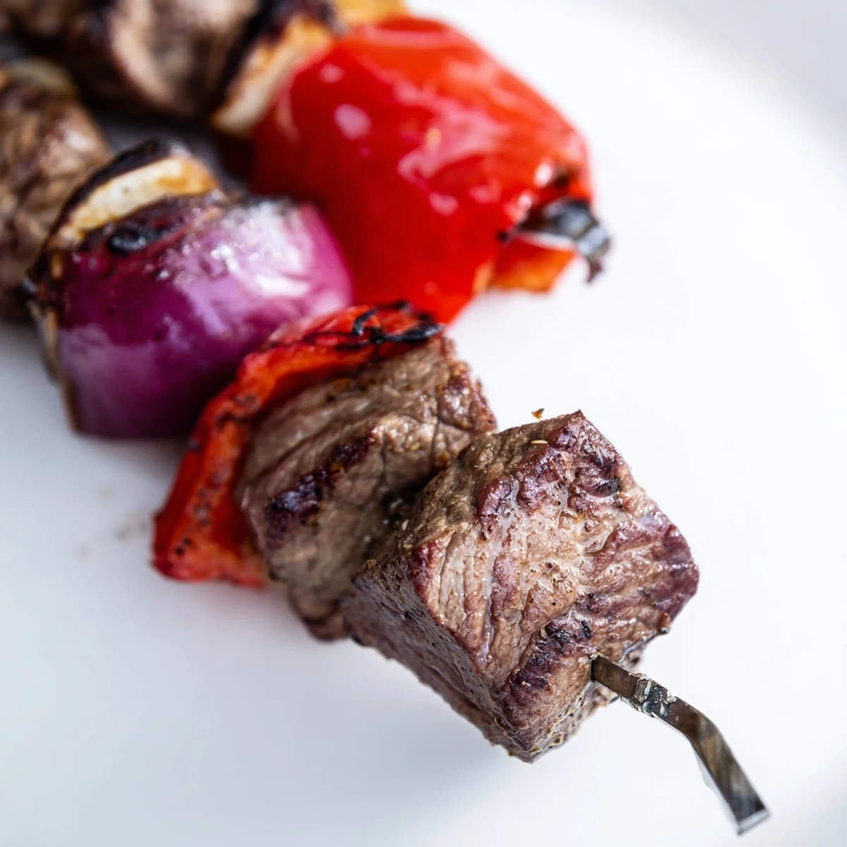 Tender grilled Beef Kebabs with Bell Peppers and Red Onion garnished with fresh herbs for a barbecue dinner.