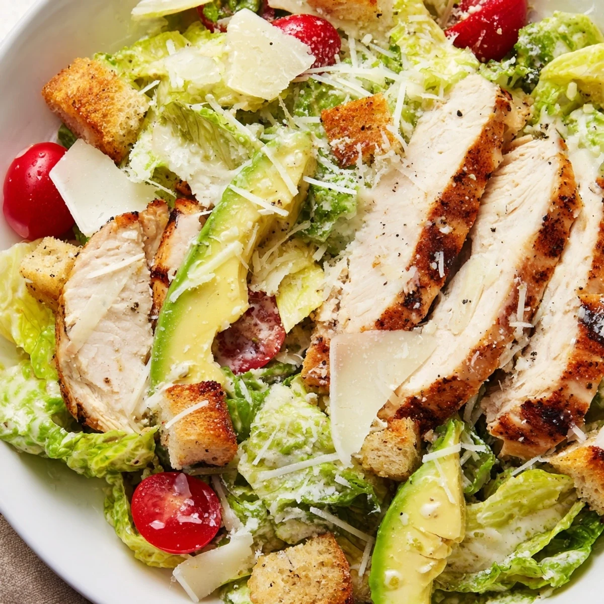 Grilled slices of Chicken Caesar Salad with Avocado on crisp romaine, topped with creamy avocado and crunchy croutons.