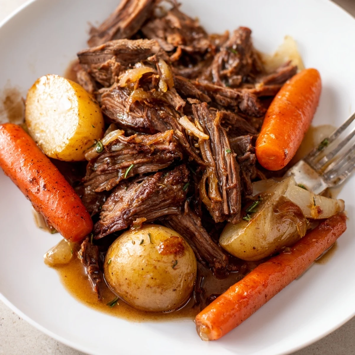Tender shredded beef, soft carrots, and potatoes swimming in a rich, savory gravy from this Slow Cooker Pot Roast with Carrots.