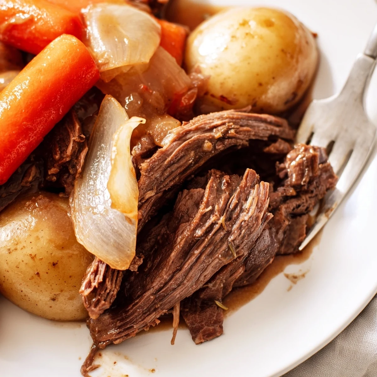A comforting Slow Cooker Pot Roast with Carrots steaming beside golden potatoes and onions on a rustic dinner table.