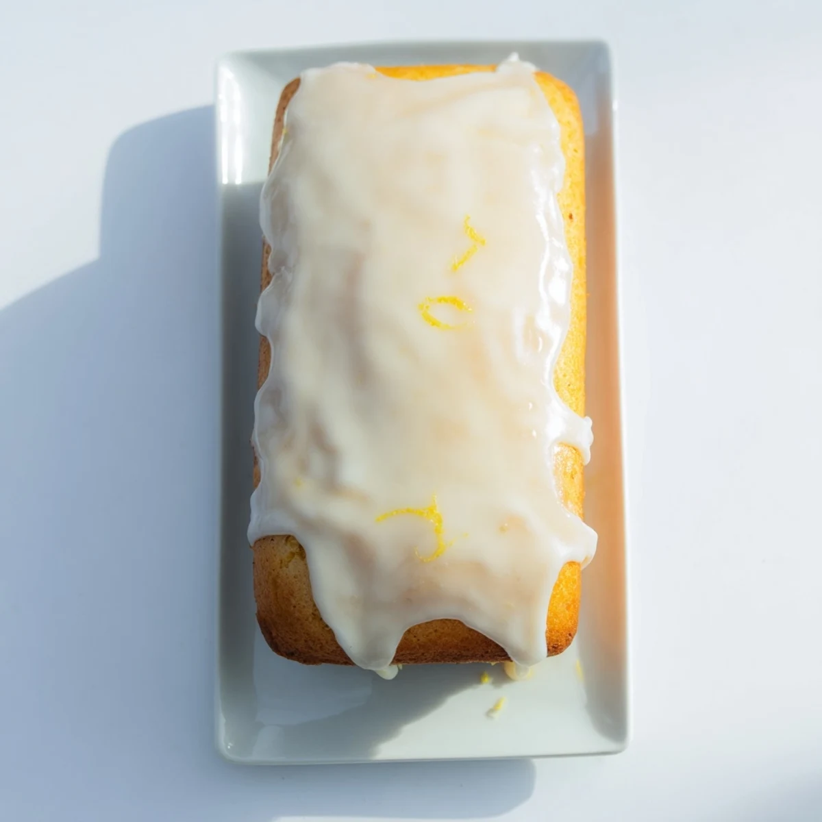 A freshly baked, moist Lemon Loaf Cake drizzled with sweet lemon icing, served on a wooden board.