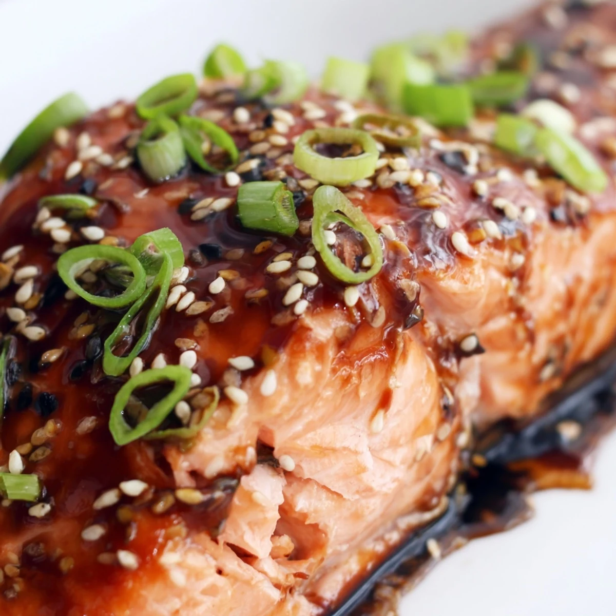 Asian-inspired baked salmon with teriyaki glaze, topped with green onions and sesame seeds.