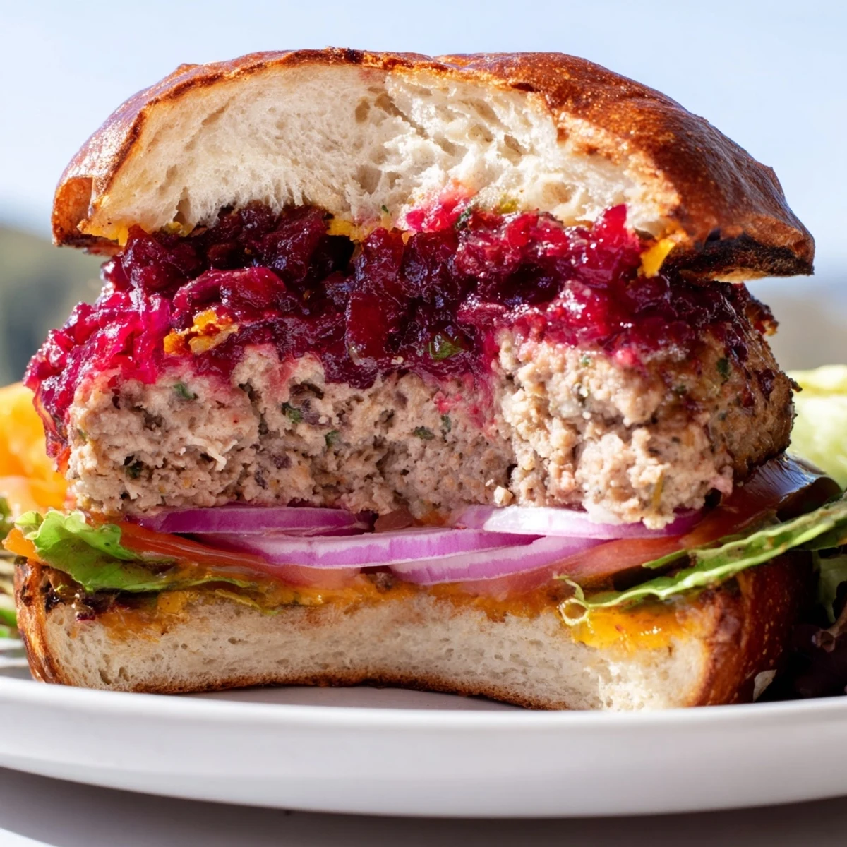 Golden turkey burger with homemade cranberry sauce and crisp lettuce, paired with sweet potato fries on a wooden board for a festive dinner.
