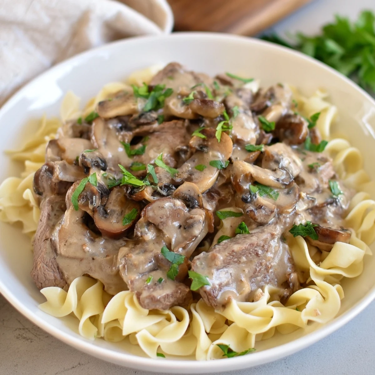 Close-up of creamy Beef Stroganoff with mushroom gravy spooned over egg noodles, a classic Russian-style family dinner ready to serve.