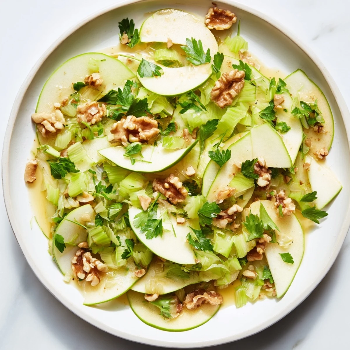 A vibrant bowl of Green Apple and Celery Salad with Walnuts, showcasing crisp apple slices, pale celery ribbons, and toasted nut halves glistening with a light vinaigrette.