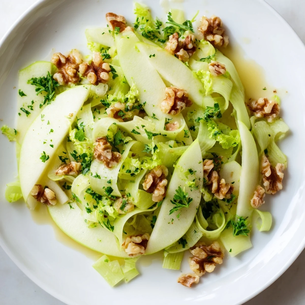 Green Apple and Celery Salad with Walnuts features tart apple wedges, crunchy celery, and toasted walnuts tossed in a tangy Dijon dressing, garnished with fresh parsley.