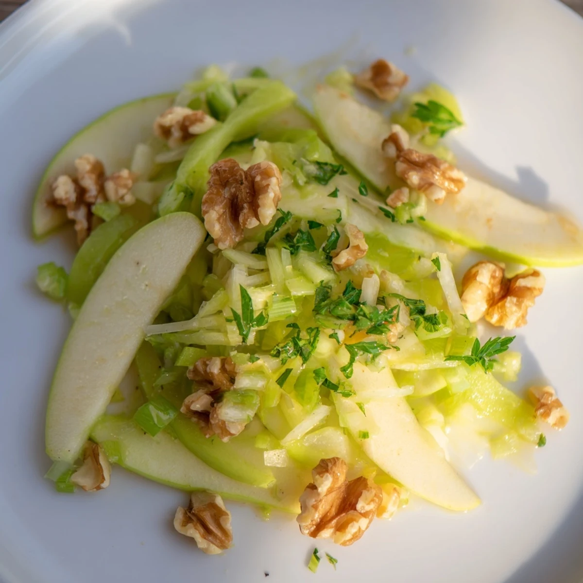 Served on a white platter, this Green Apple and Celery Salad with Walnuts highlights thinly sliced Granny Smith apples, celery, and walnuts dressed in a light vinaigrette.