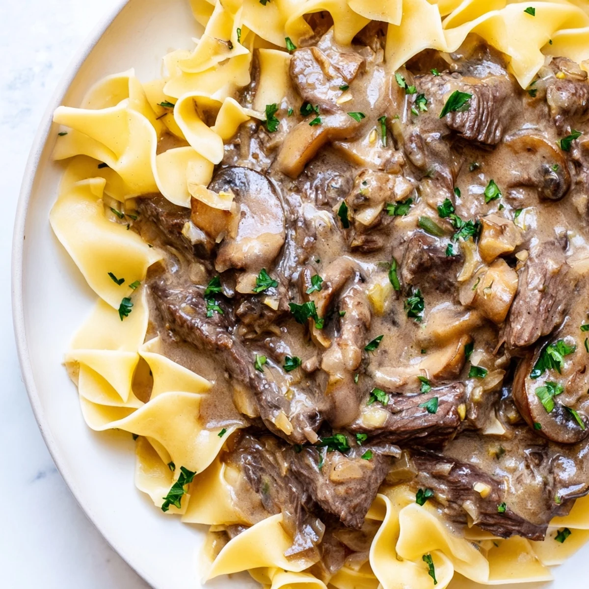 Rich Beef Stroganoff over Egg Noodles served on a plate ready for a family dinner.
