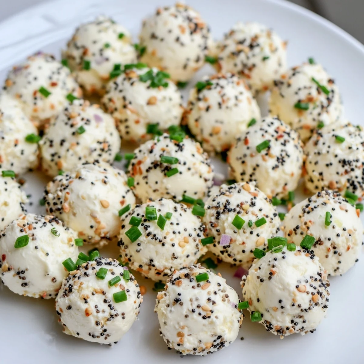 Freshly rolled Everything Bagel Cottage Cheese Bites coated in sesame and poppy seeds on a platter.