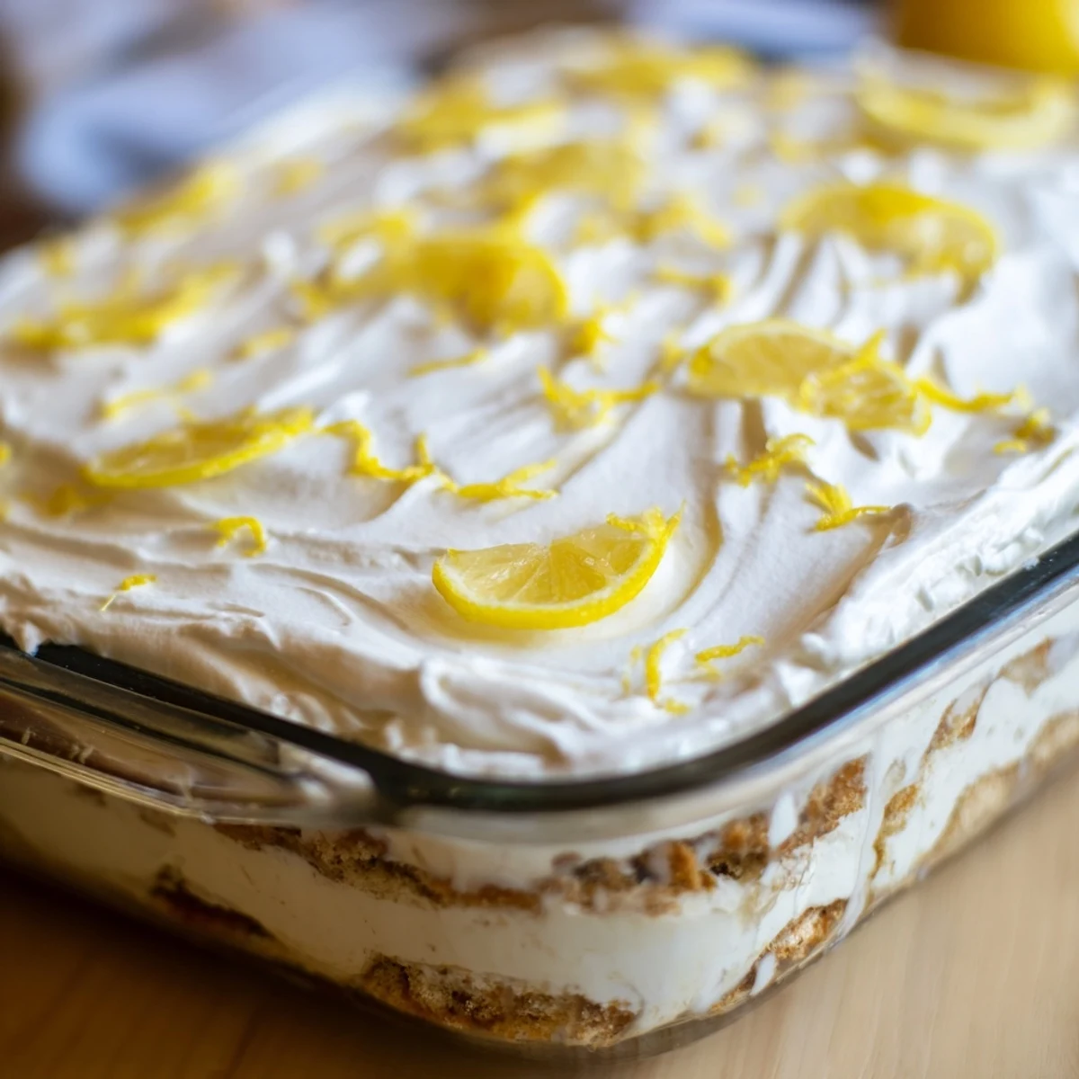 Layers of lemon syrup-soaked ladyfingers and mascarpone cream in a glass dish for Easy Lemon Tiramisu No Bake Dessert.