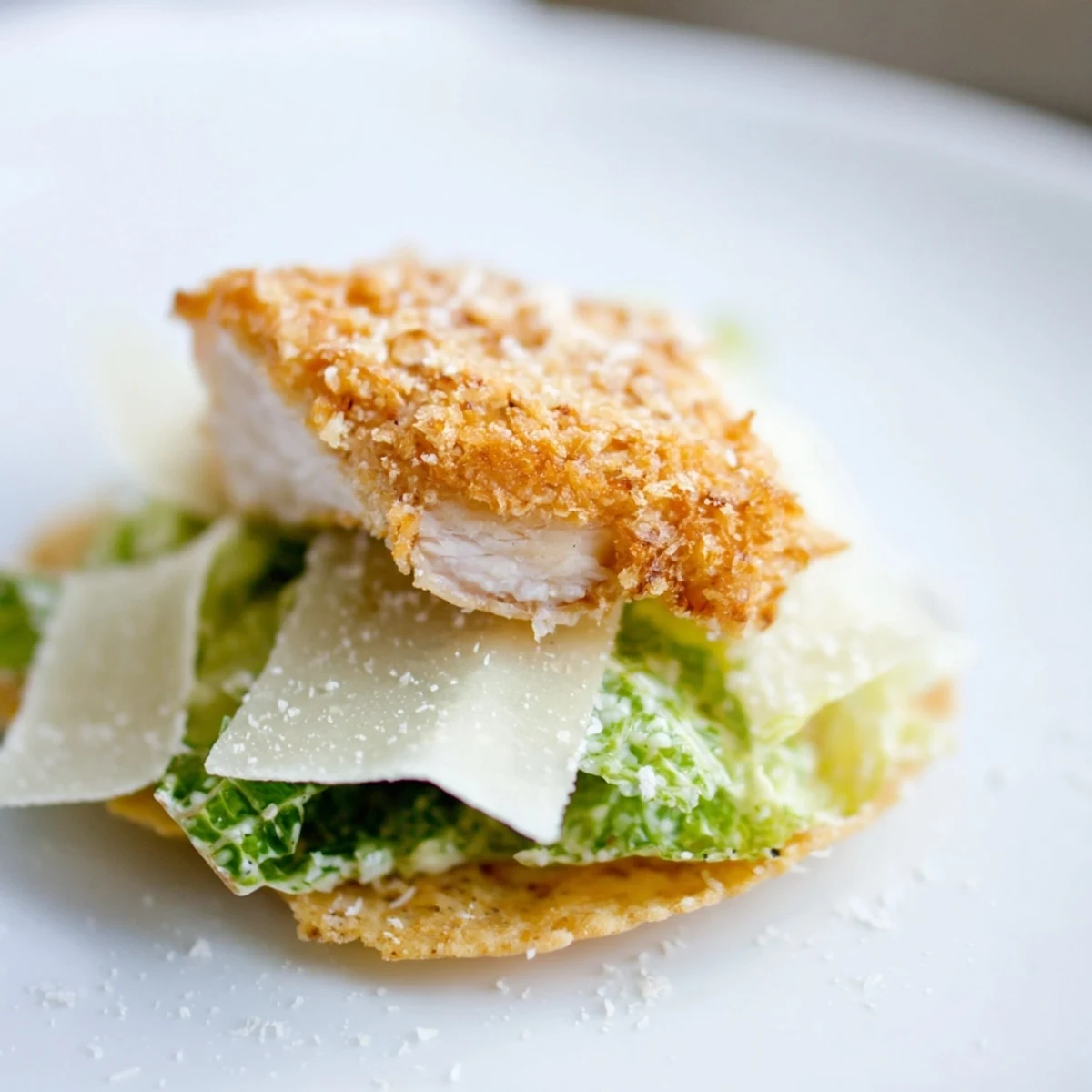 Homemade crispy chicken caesar salad chips arranged on a platter with fresh lemon wedges for squeezing over the bite-sized appetizer.