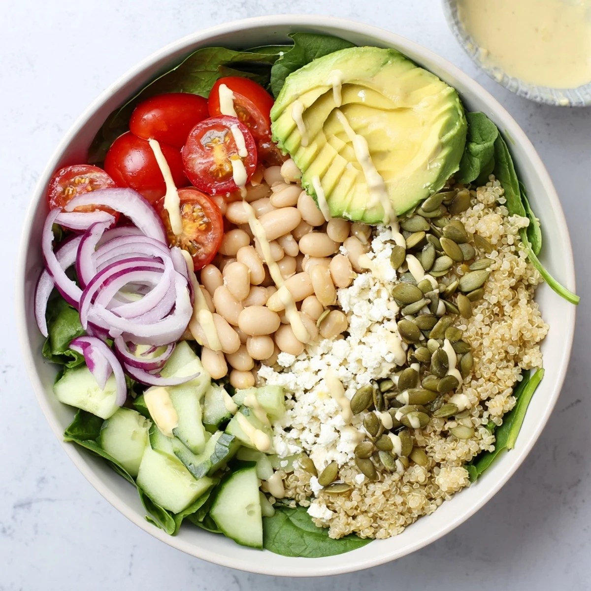 Fresh spinach and creamy white beans in the Spinach & White Bean Ultimate Protein Power Bowl, topped with quinoa and avocado slices.