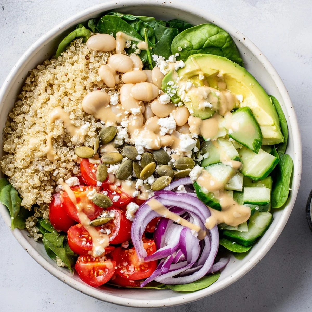 Overhead view of a healthy Spinach & White Bean Ultimate Protein Power Bowl garnished with pumpkin seeds and feta, served as a main dish.