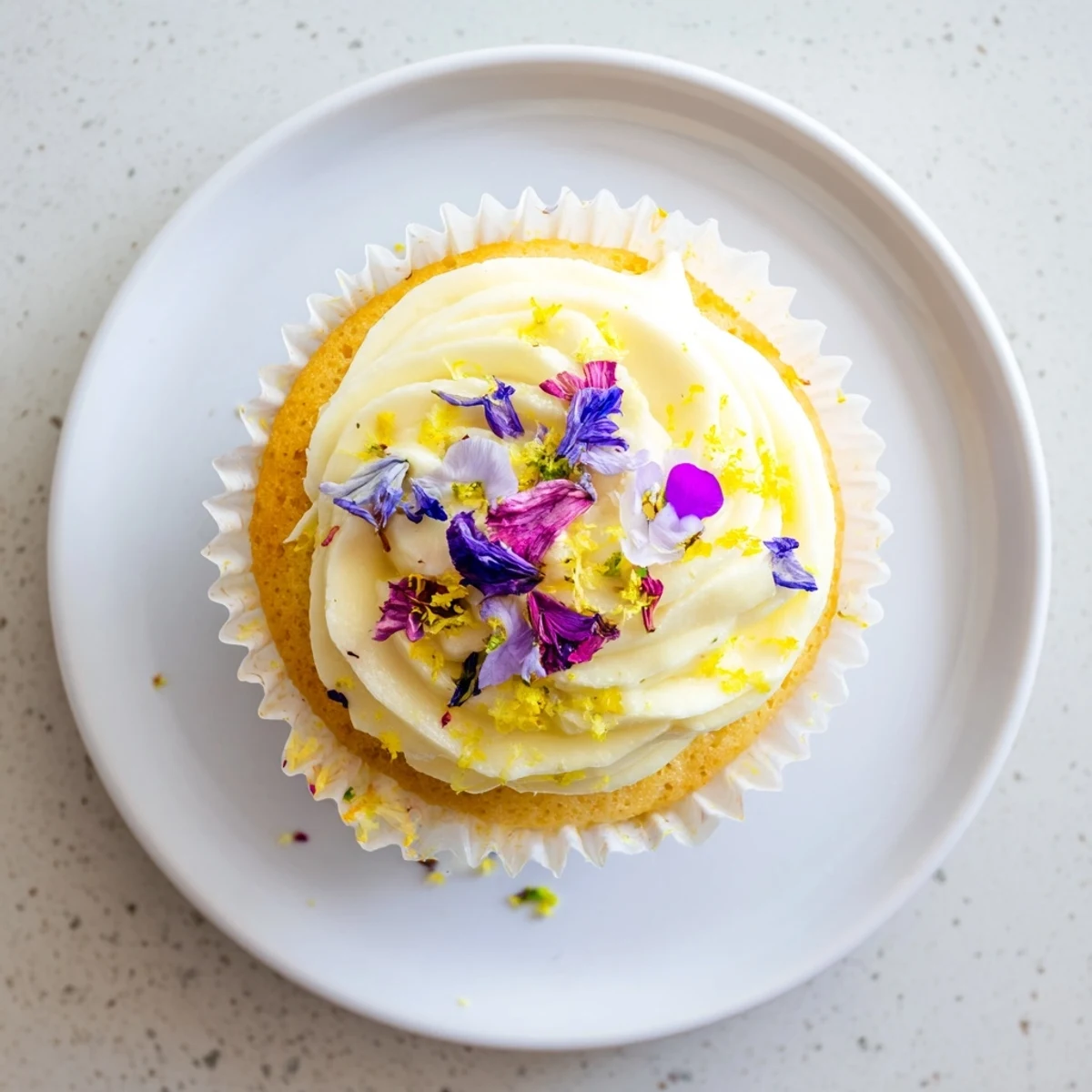 Plated elderflower cupcakes beside a steaming cup of Earl Grey tea, ready for afternoon tea.