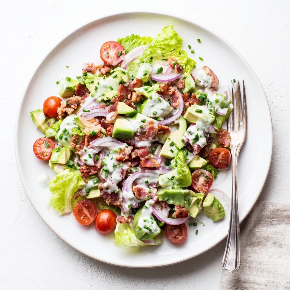 Close-up of Crispy Bacon Keto BLT Salad showing chopped romaine, halved cherry tomatoes, and creamy avocado slices.