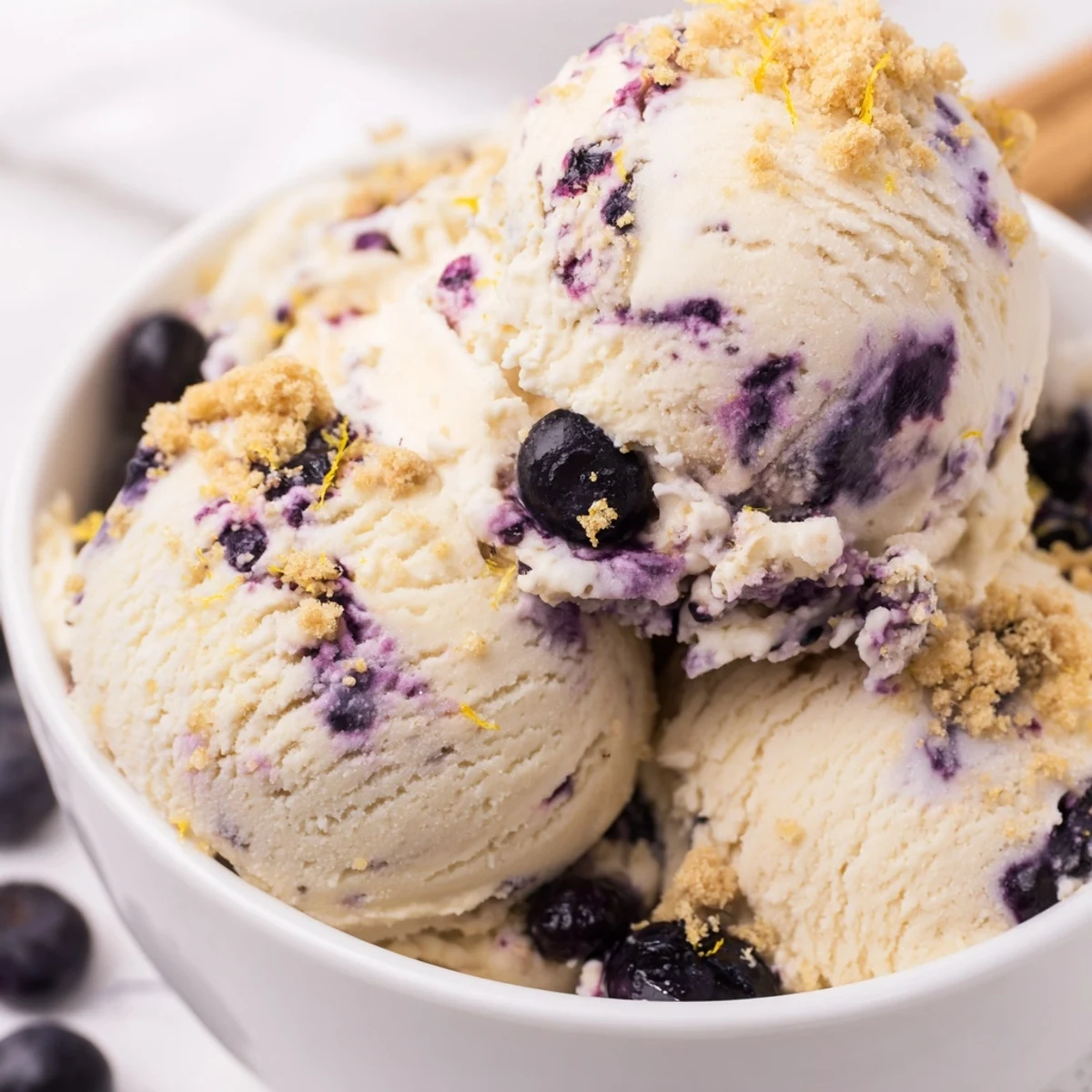 Summer dessert: homemade Lemon Blueberry Cheesecake Ice Cream with velvety texture and sweet blueberry sauce ready to serve.