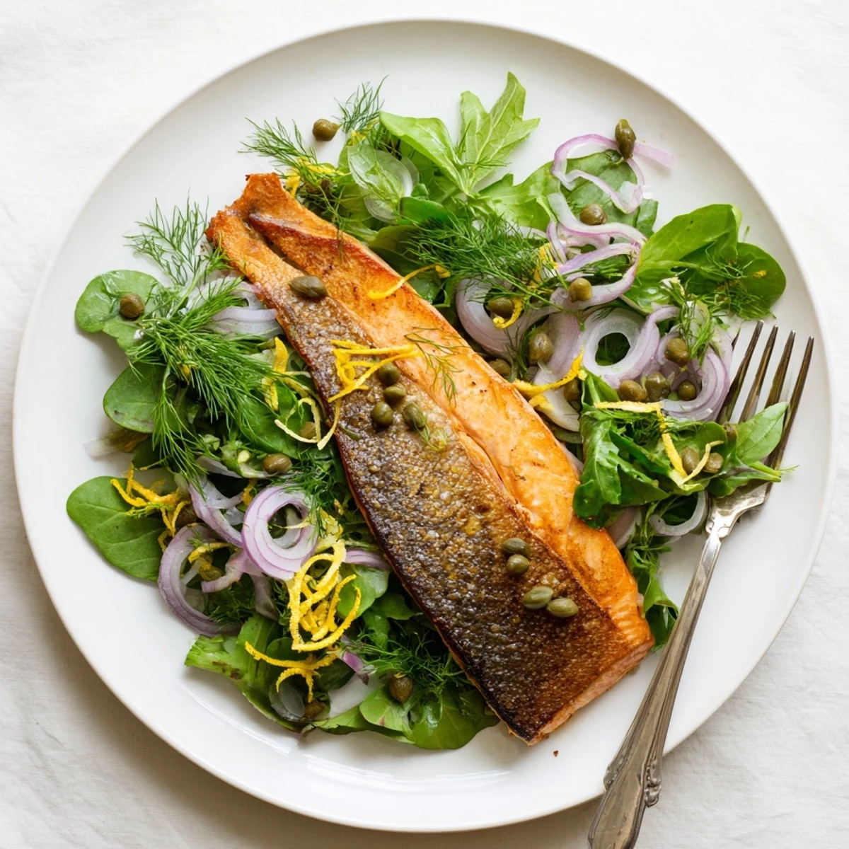 A close-up of flaky Tasmanian Atlantic salmon with crisp skin, resting on a bed of peppery arugula and herbs.