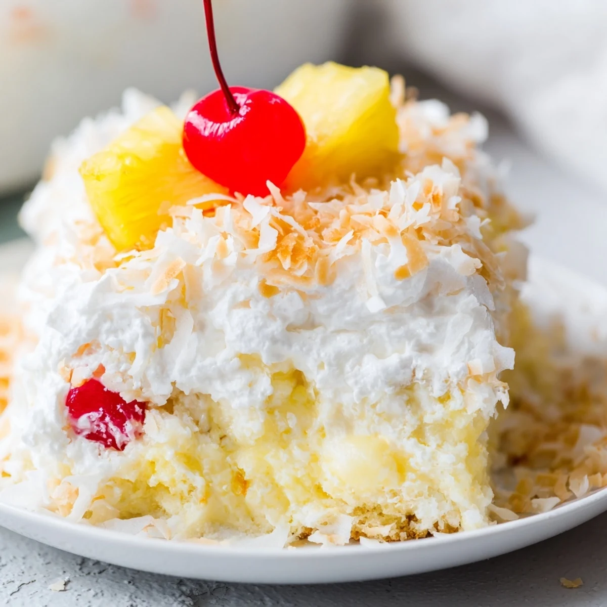 Chilled Hawaiian Poke Cake served with maraschino cherries and tropical pineapple garnish on a plate.