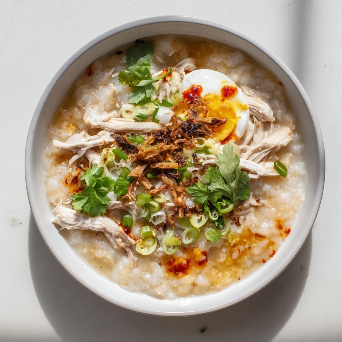 Steaming bowl of savory Asian fusion rice porridge with shredded holiday turkey and fresh green garnishes