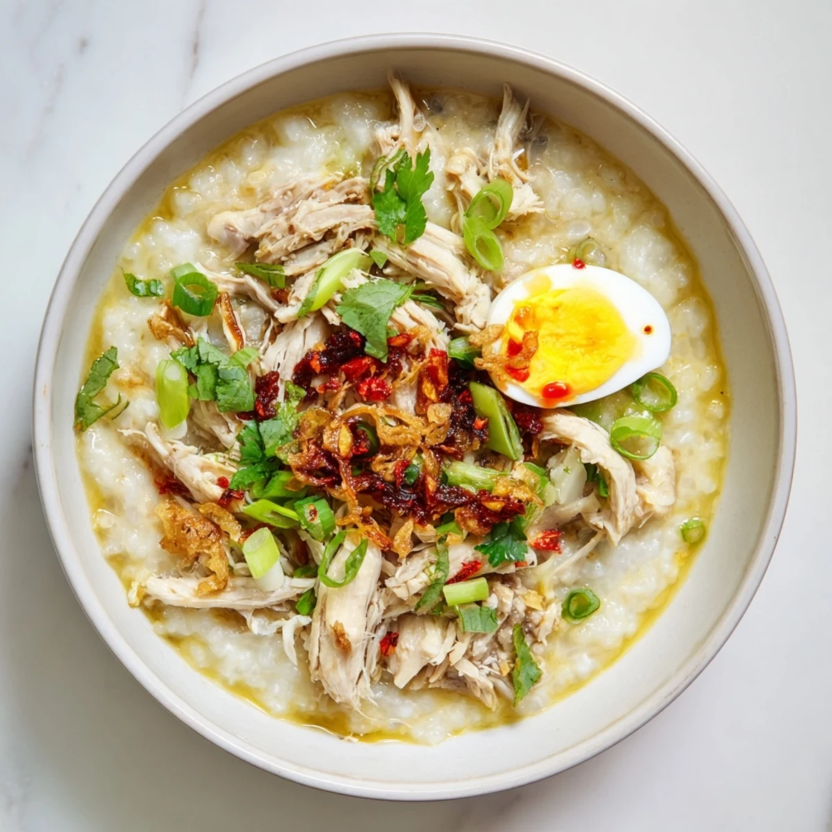 Golden turkey congee simmered with ginger and garlic, garnished with boiled egg slices and chili oil