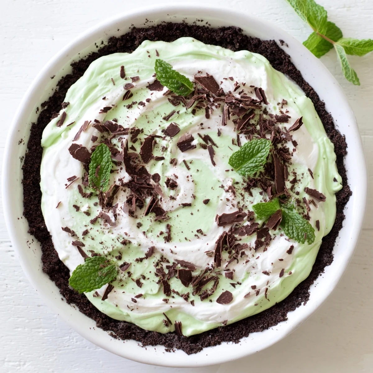 Chocolate crusted Shamrock Swirl Pie slice garnished with mint leaves and chocolate shavings