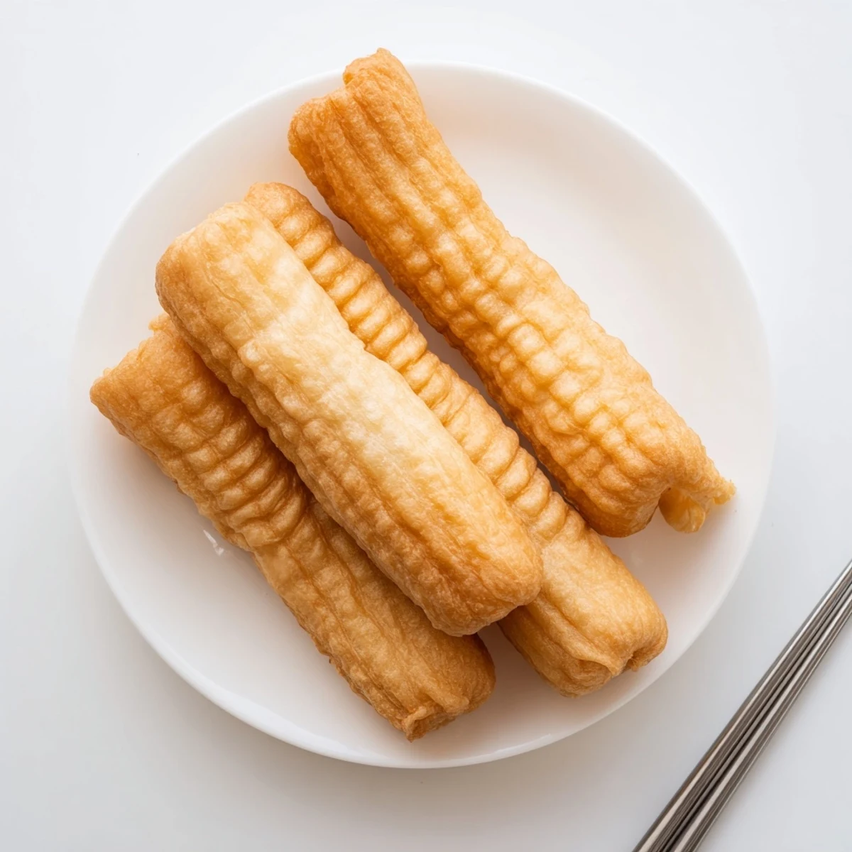 Puffed golden Youtiao fried dough strips stacked on wire rack ready for breakfast