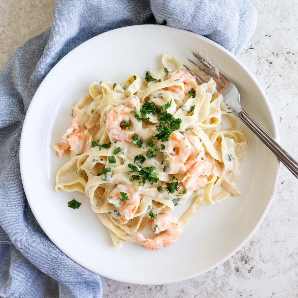 Tossed fettuccine pasta in rich white sauce with plump shrimp and fresh parsley garnish