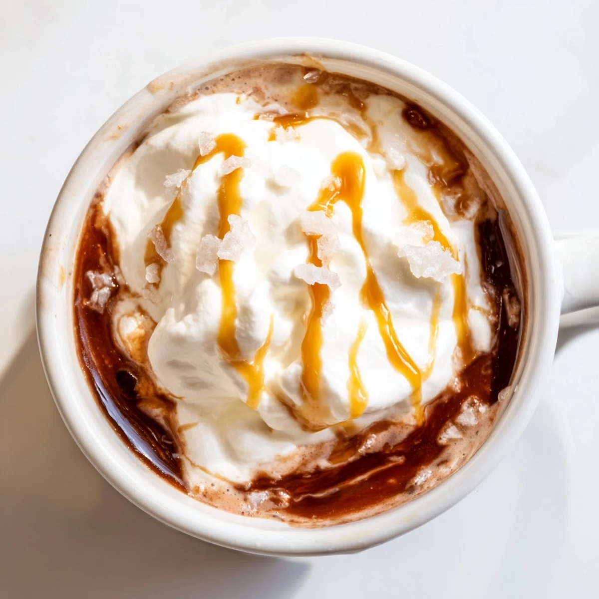 Creamy salted caramel hot chocolate drizzled with extra caramel sauce and dusted with sea salt garnish
