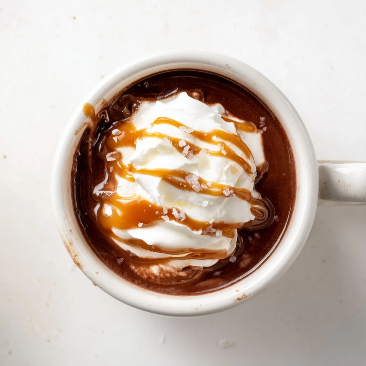 Steaming salted caramel hot chocolate served with whipped cream topping and caramel swirl on a cold day