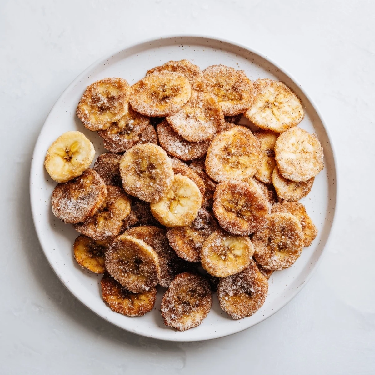 Bite-sized banana chips sprinkled with cinnamon sugar after air frying until golden and crunchy