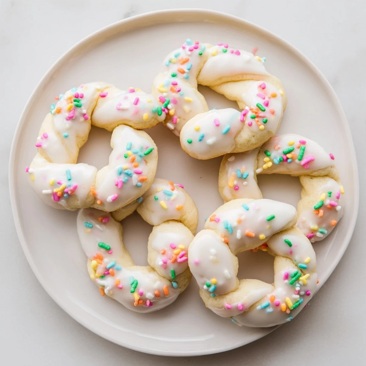Citrus flavored Italian Easter cookies arranged on a decorative platter with sweet white glaze and rainbow sprinkles