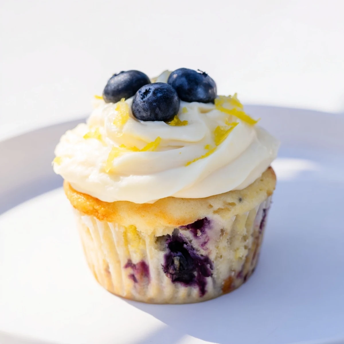 Golden cupcakes studded with fresh blueberries crowned with fluffy lemon cream cheese frosting and zest
