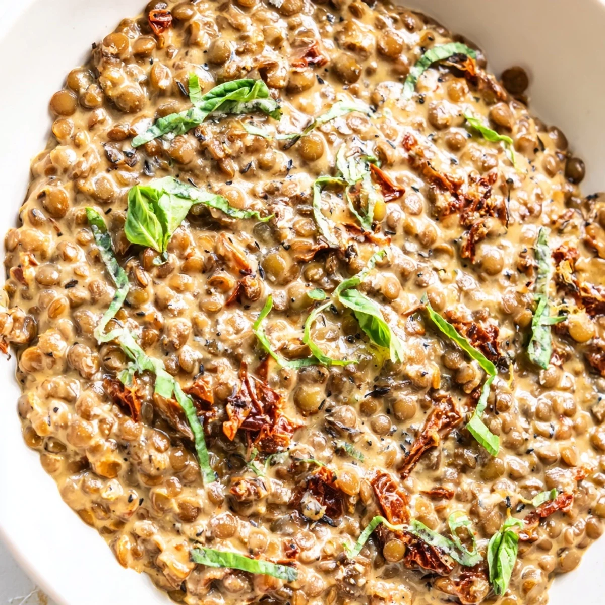 Creamy Marry Me Lentils in rustic skillet with sun-dried tomatoes and fresh basil garnish