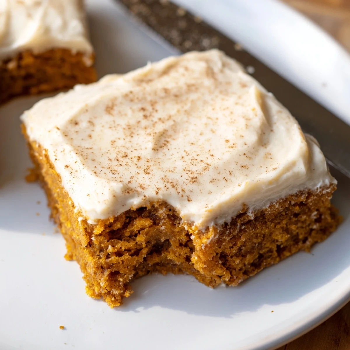 Cream cheese frosted pumpkin bars sliced into neat squares on a rustic cutting board