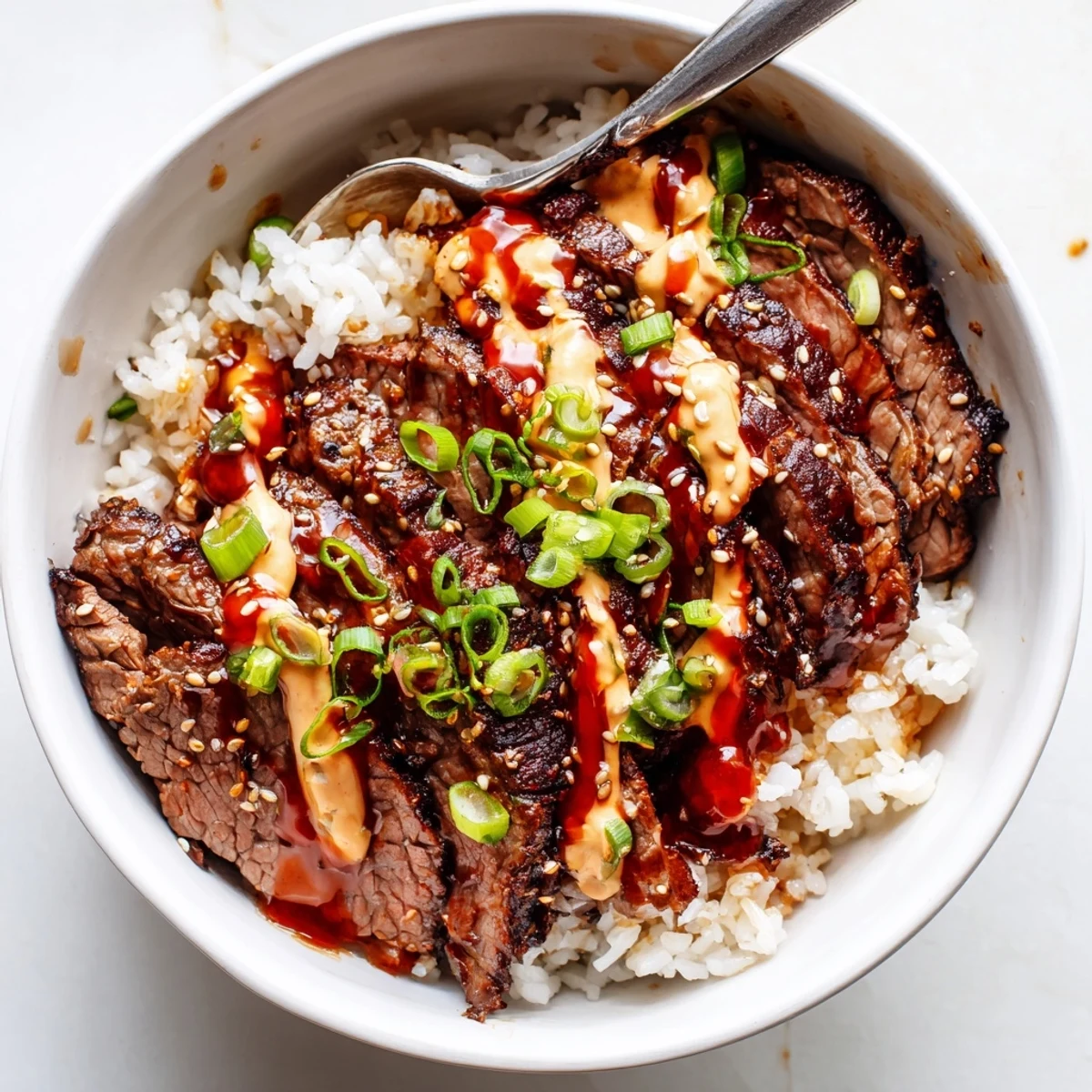 Caramelized Korean BBQ steak rice bowls drizzled with spicy cream sauce over fluffy rice