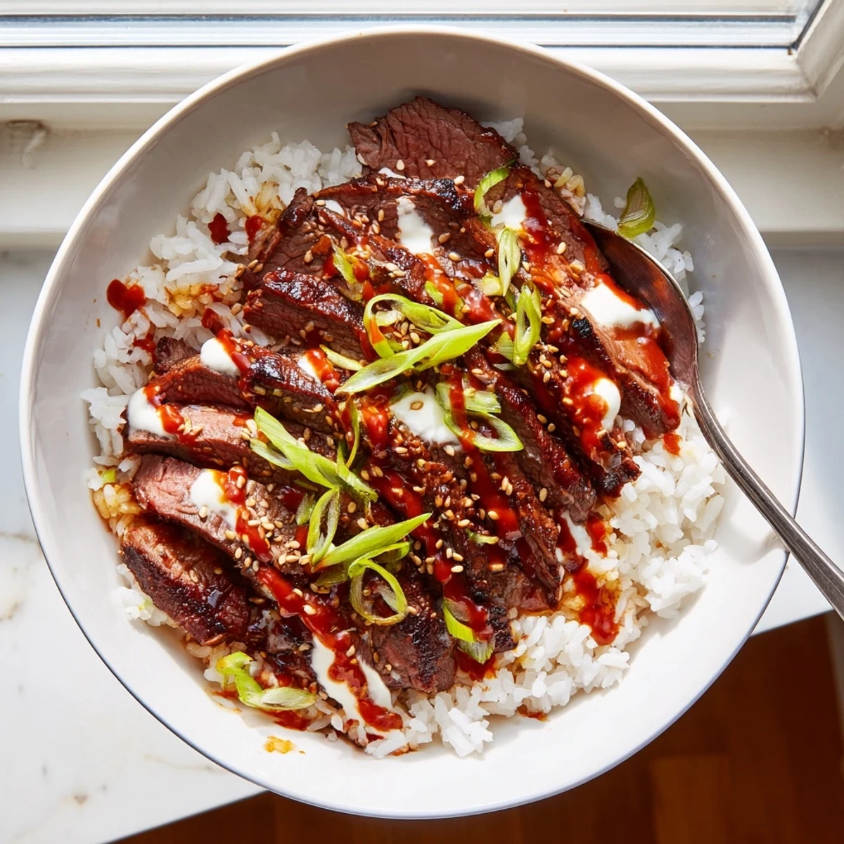 A generous Korean BBQ steak rice bowl topped with kimchi and a bold spicy cream sauce