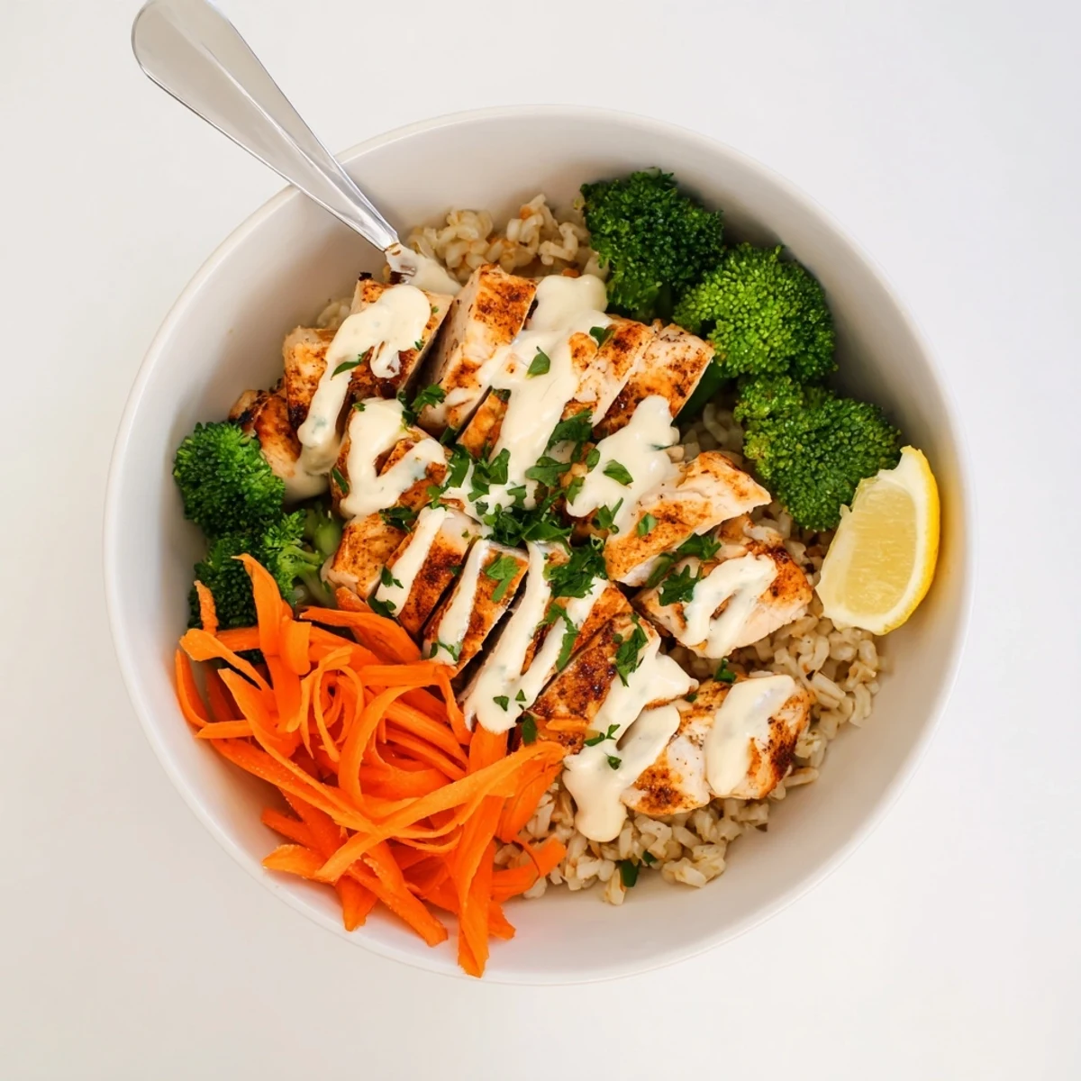 Tender sliced grilled chicken breast over steamed broccoli drizzled with creamy garlic sauce in a bowl
