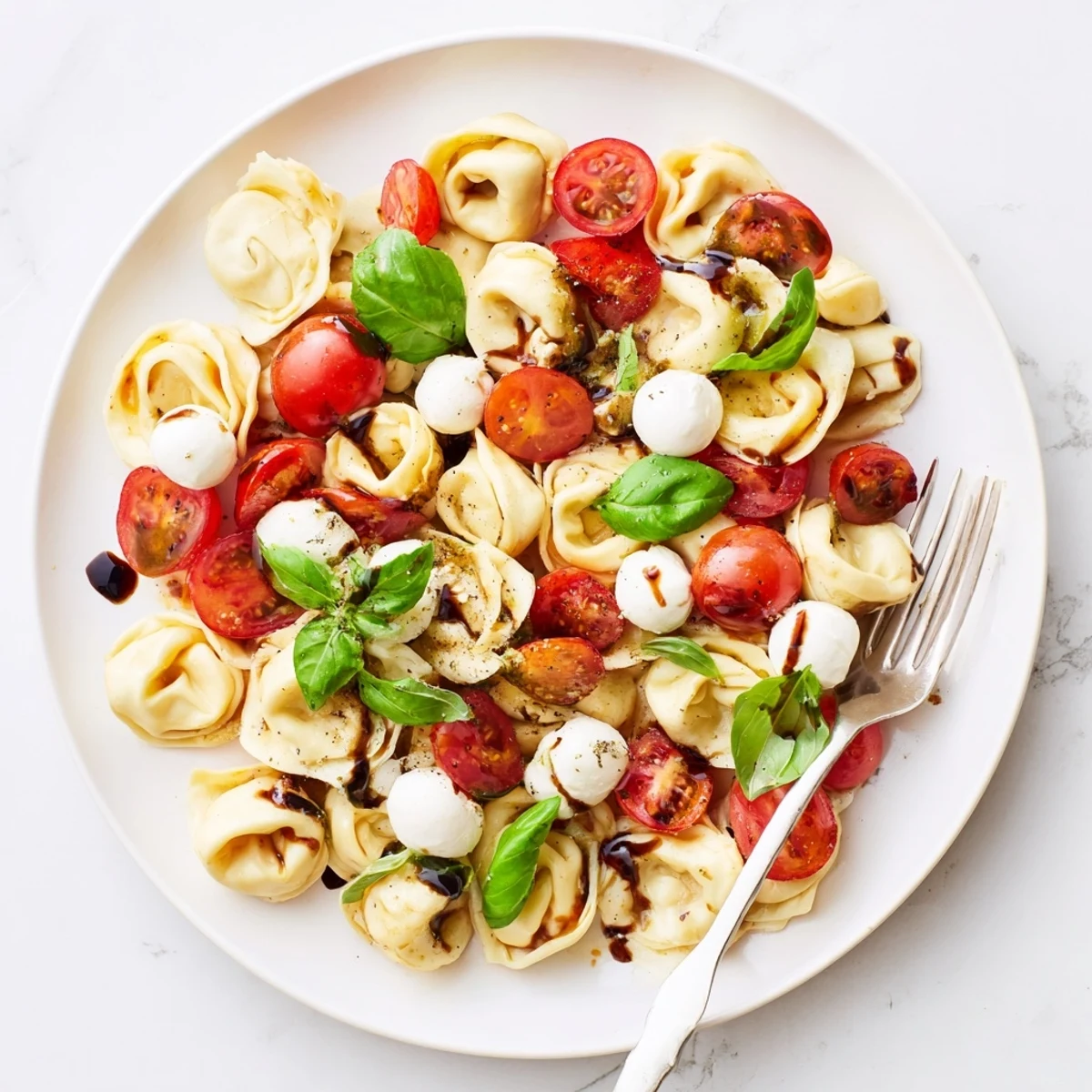 Colorful bowl of tortellini Caprese salad with cherry tomatoes, fresh basil, and mozzarella