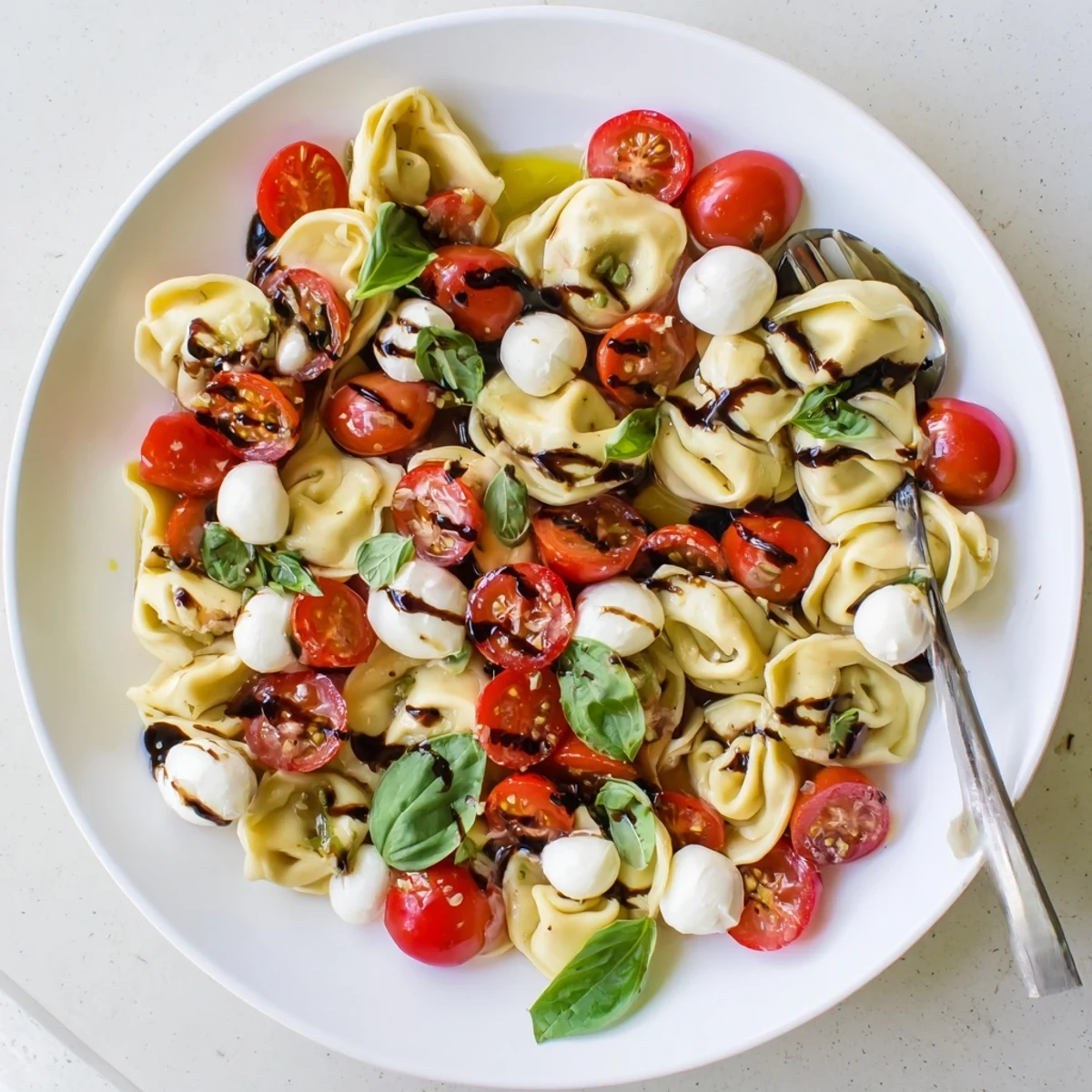 Cheese tortellini tossed with juicy tomatoes, basil leaves, and mozzarella in a light balsamic dressing