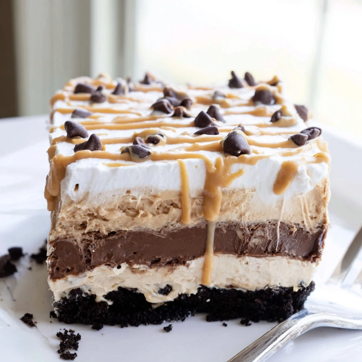 Creamy Peanut Butter Layered Delight with chocolate pudding and whipped topping in a glass baking dish