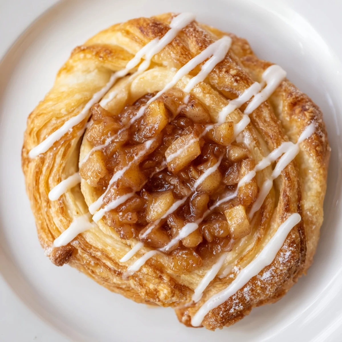 Warm apple cheese danishes drizzled with sweet icing beside a steaming coffee mug