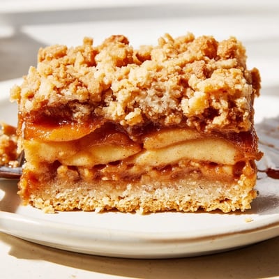 Warm caramel apple crumb bars cut into squares drizzled with extra caramel sauce