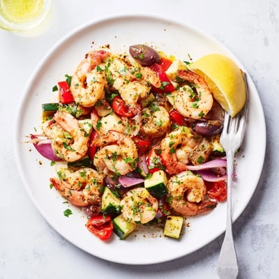 Golden pan-seared Mediterranean shrimp skillet garnished with fresh parsley and bright lemon wedges
